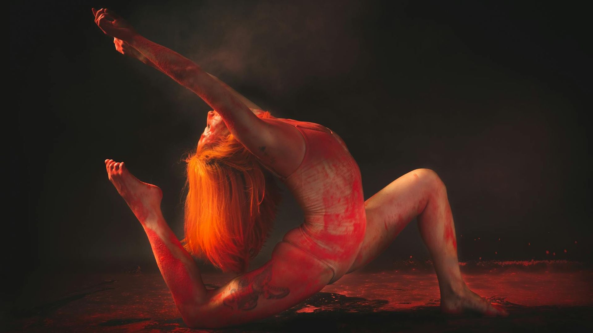 Silhouette of a person in a dynamic stretching pose against a dark, atmospheric background.